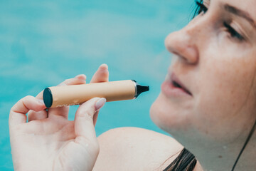 Woman smoking with electronic cigarette. Young woman smoking electronic cigarette in outdoors pool