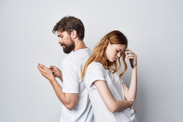 a young couple family with phones in hand communication light background