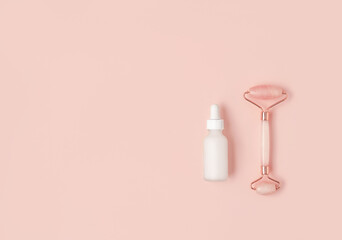 Beautiful composition of white mockup serum bottle and pink quarts stone face roller on pink background. Anti-ageing cosmetics concept. Creative trendy cosmetics flat lay with copy space.