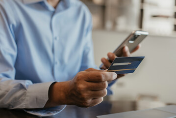 Hands holding credit card and using smartphone and laptop. Online shopping.