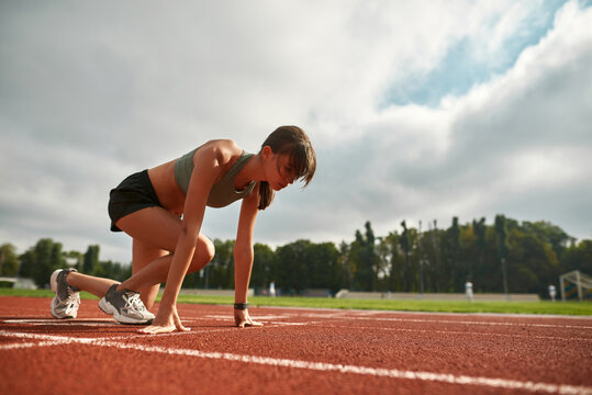 Concentrated Young Female Athlete Getting Ready To Start Running On Track Field In The Daytime