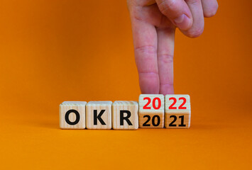 OKR, objectives and key results symbol. Businessman turns cubes with words OKR 2021 and OKR 2022 on beautiful orange background. Business, OKR 2022, objectives and key results concept. Copy space.