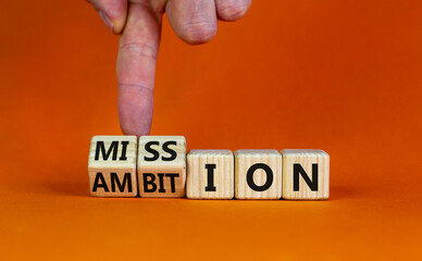 Do your mission with ambition. Businessman turns wooden cubes and changes the word mission to ambition. Beautiful orange table, orange background, copy space. Business, mission or ambition concept.