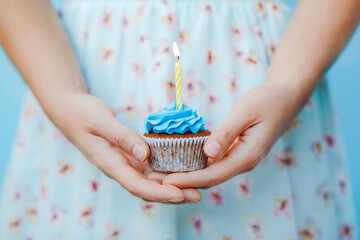 woman in blue dress holding birthday cupcake