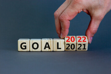Planning 2022 goal new year symbol. Businessman turns a wooden cube and changes words 'Goal 2021' to 'Goal 2022'. Beautiful grey background, copy space. Business, 2022 goal new year concept.