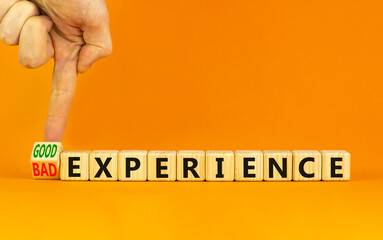 Good or bad experience symbol. Businessman turns a wooden cube, changes words bad experience to good experience . Beautiful orange background, copy space. Business, good or bad experience concept.