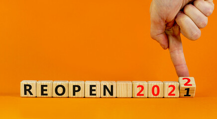 2022 reopen new year symbol. Businessman turns wooden cubes and changes words 'Reopen 2021' to...