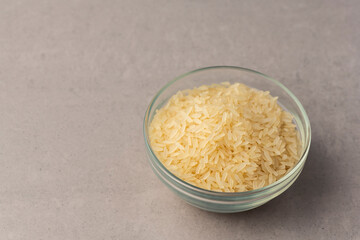 Raw white rice in a bowl cooking concept on grey textured surface