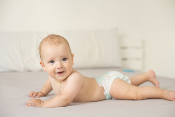 Adorable baby boy in white sunny bedroom. Newborn child relaxing in bed. Nursery for young children. Family morning at home. New born kid