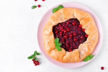 Galette with lingonberry on the white table. Sweet pie with forest berries on pastry dough. Top view