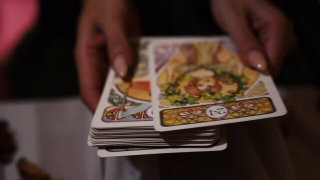 A mystical sorceress shuffles the tarot cards in white with a pattern. Mystical activities and hobbies.