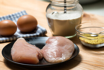 Chicken fillet on a cutting board ready for grilling, selective focus. Raw chicken breast with grill pan, flour and spices. Chicken steaks for cooking
