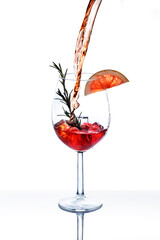Cocktail splash in wine glass with citrus fruit slice, rosemary and ice isolated on white...
