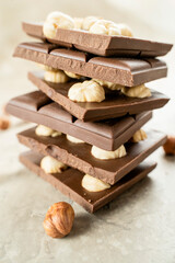 Tower of chocolate pieces with hazelnuts on a white background. Milk chocolate with nuts. Confectionery craft on table stack for Delicious Chocolate