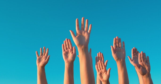 Raised hands against blue sky