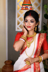 Portrait of beautiful Indian Bengali female woman in red and white traditional ethnic saree and jewellery in studio lighting indoor. Indian culture, religion and fashion - obrazy, fototapety, plakaty