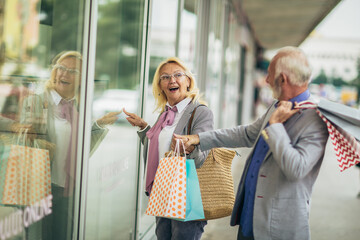 Senior couple carrying shopping bags and enjoying to shopping