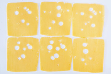 slices of hard cheese with holes on white