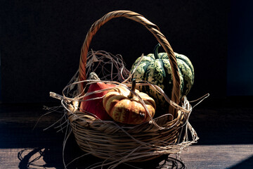 Ornamental pumpkins in green, yellow and red are in a wicker basket.