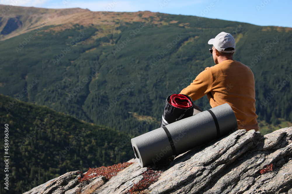 Wall mural tourist with sleeping bag and mat on mountain peak