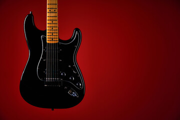 Black electric guitar on red background