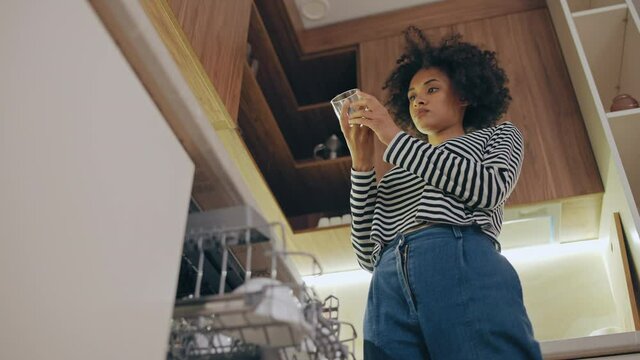 Happy housewife taking glass from dishwasher in kitchen, timesaving technology