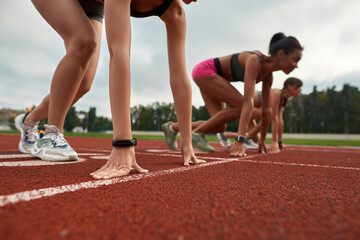 Closeup view of professional female runners ready to start race on track field at stadium