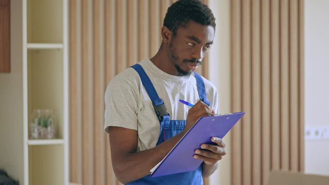Black repairman inspecting home problems, writing in document, maintenance