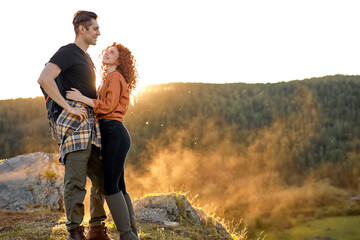 Female and male hikers walking in summer mountains in countryside. Happy couple talking together....