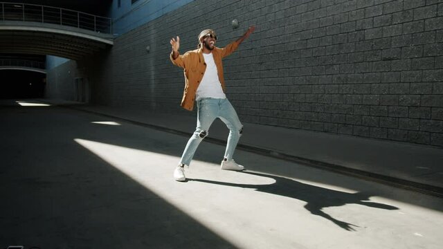 Slow motion portrait of happy African American guy moving outdoors dancing and smiling on sunny day. Unique people and creative activities concept.