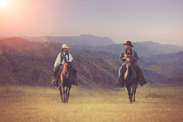cowboys horseback riding at sunset time with sunlight ray sky nature mountain background.