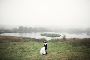 Wedding couple on the nature is hugging each other. Beautiful model girl in white dress. Man in suit
