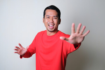 Naklejka premium Adult Asian man showing happy face expression while running forward to reach something