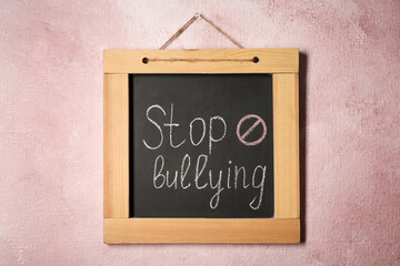 Blackboard with phrase Stop Bullying and prohibition sign on pink wall