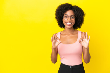 Fototapeta na wymiar Young African American woman isolated on yellow background showing ok sign with two hands