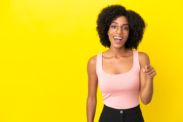 Fototapeta na wymiar Young African American woman isolated on yellow background surprised and pointing front