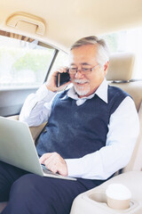 Business senior rich man Stock trader player in suit working with laptop computer and using a smart phone in his car , concept for senior business success