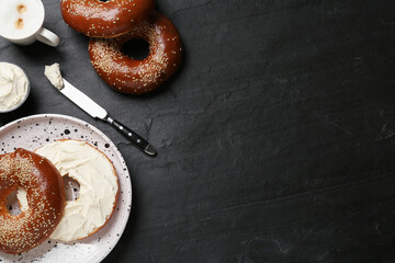 Delicious bagel with cream cheese and coffee on black table, flat lay. Space for text