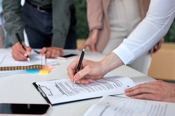 successful business agreement, deal concept. cropped Business people signing official contract, formal document with pen on desk in modern bright office in the presence of colleagues co-workers