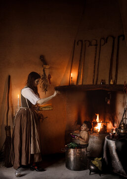 Witch with magic book conjuring over cauldron with child