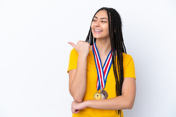 Teenager girl with braids and medals over isolated pink background pointing to the side to present a product