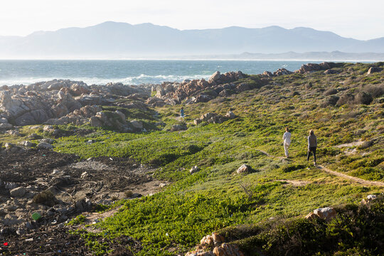 Woman and two children walking along coastal path on the Atlantic Ocean coastline, De Kelders