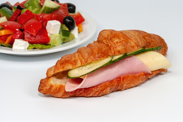 Croissant with ham and cheese, European breakfast with Greek salad. Set of sandwiches with croissants on a white b
