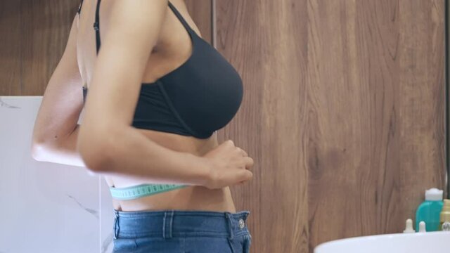 Cheerful young woman looking at measuring tape, effective diet, body weight
