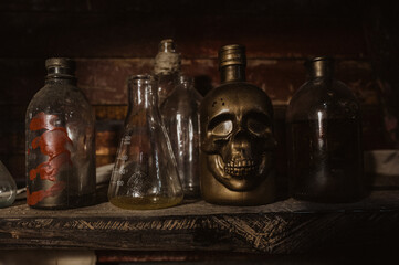 Old glass bottles, jars and flasks stand on a dark shelf in the hold of the ship next to the skull.
