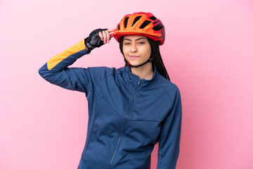 Teenager cyclist girl isolated on pink background having doubts