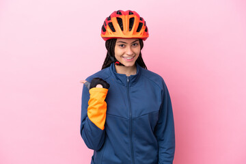 Teenager cyclist girl isolated on pink background pointing to the side to present a product