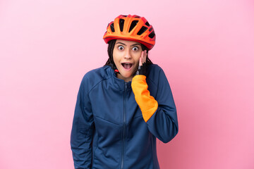 Teenager cyclist girl isolated on pink background with surprise and shocked facial expression