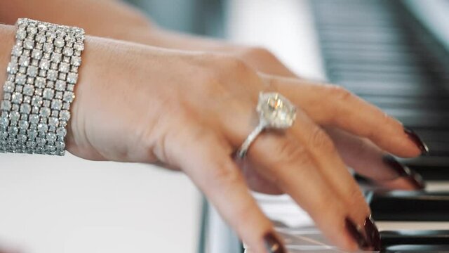 Slow motion of beautiful hands of a female lady piano player wearing a gold ring with a diamond and a bracelet
