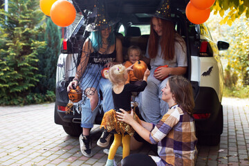 Diverse family friends celebrating Halloween in car trunk outdoors